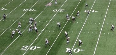 A group of football players are playing on a field with the number 20 on it