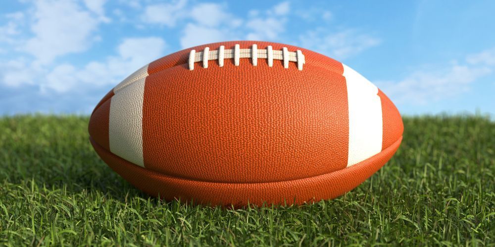 A football is sitting on top of a pile of gold coins on a field.