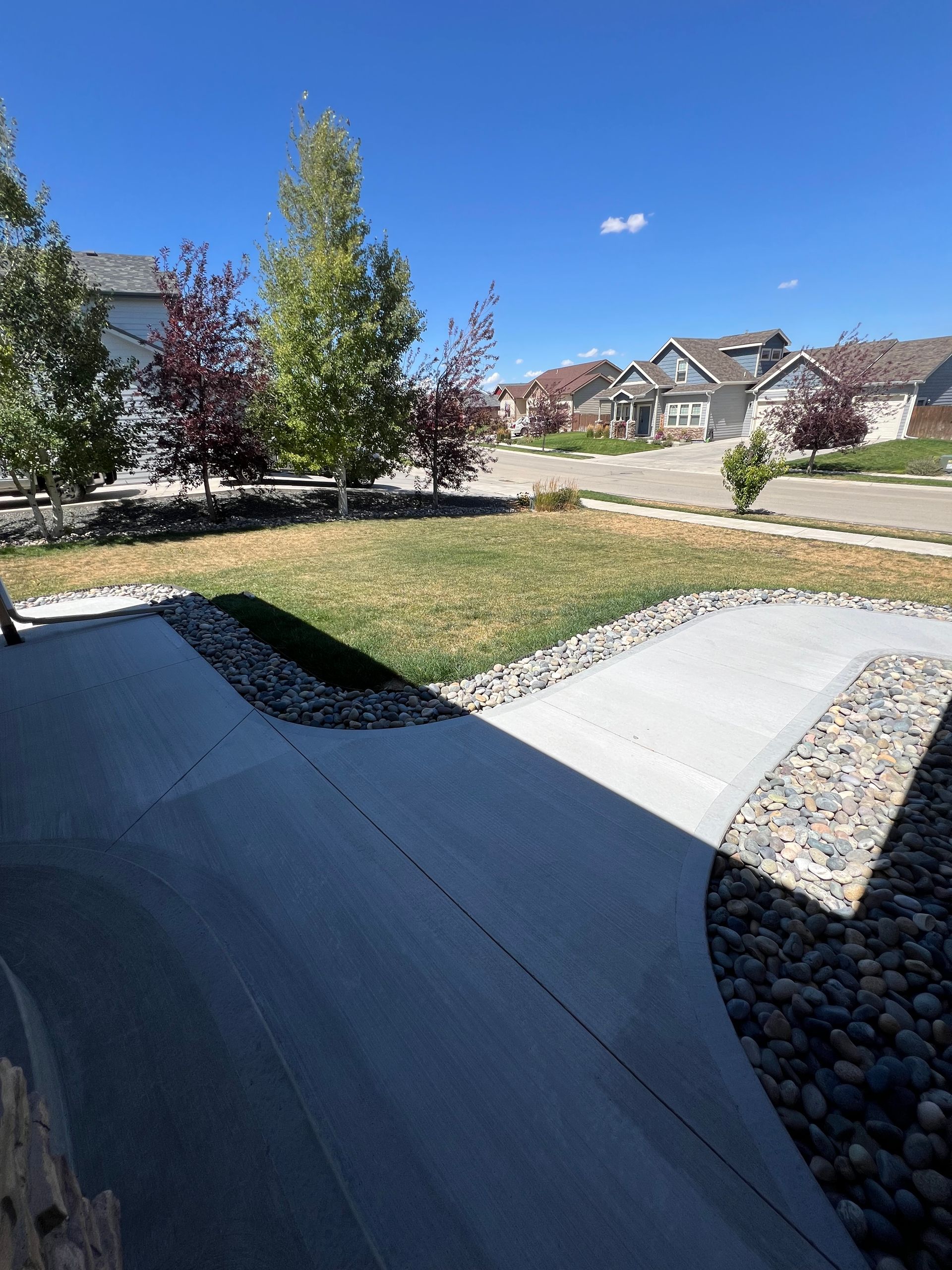 A concrete walkway leading to a house in a residential area.