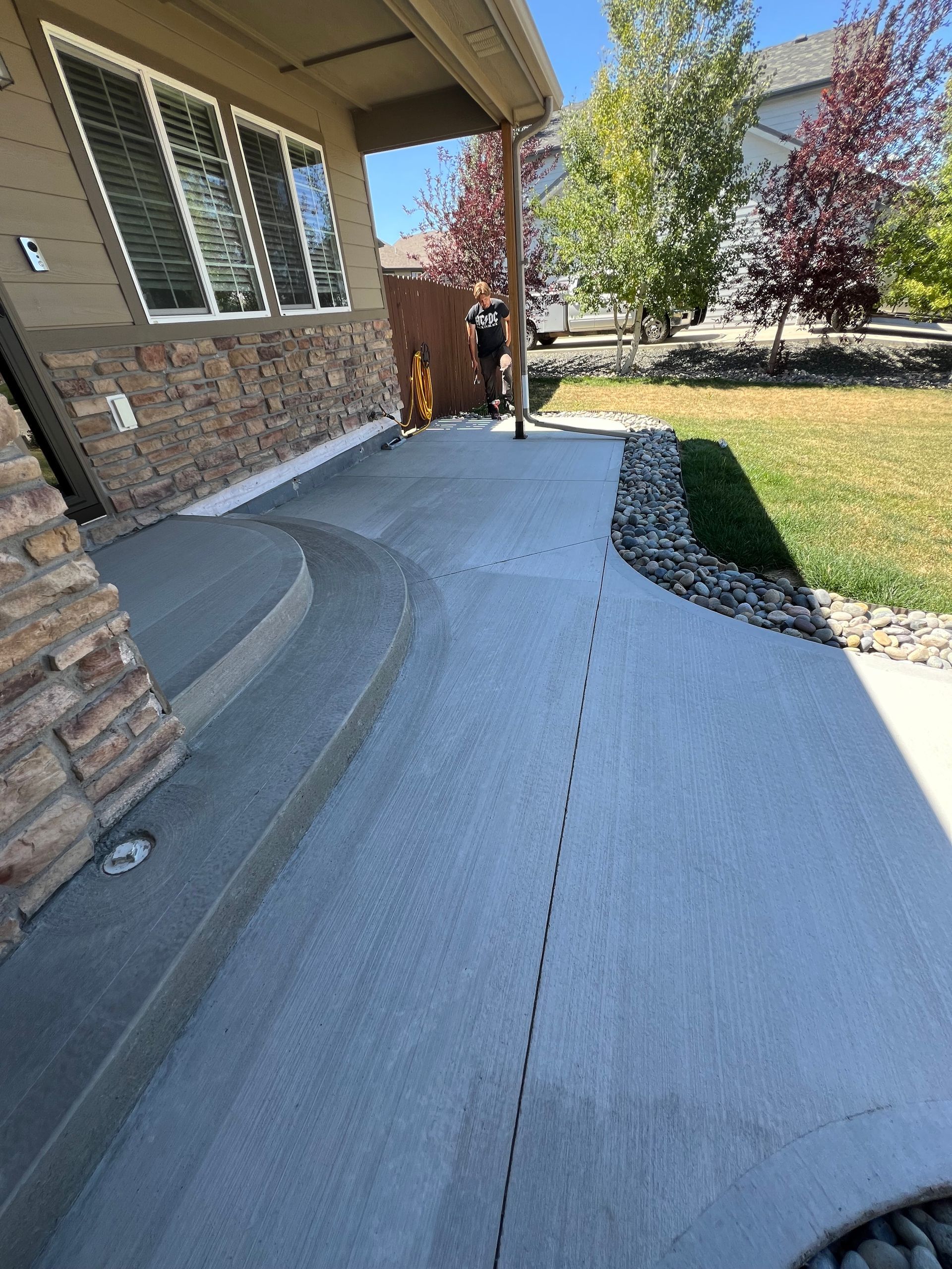 A person is standing on a sidewalk in front of a house.