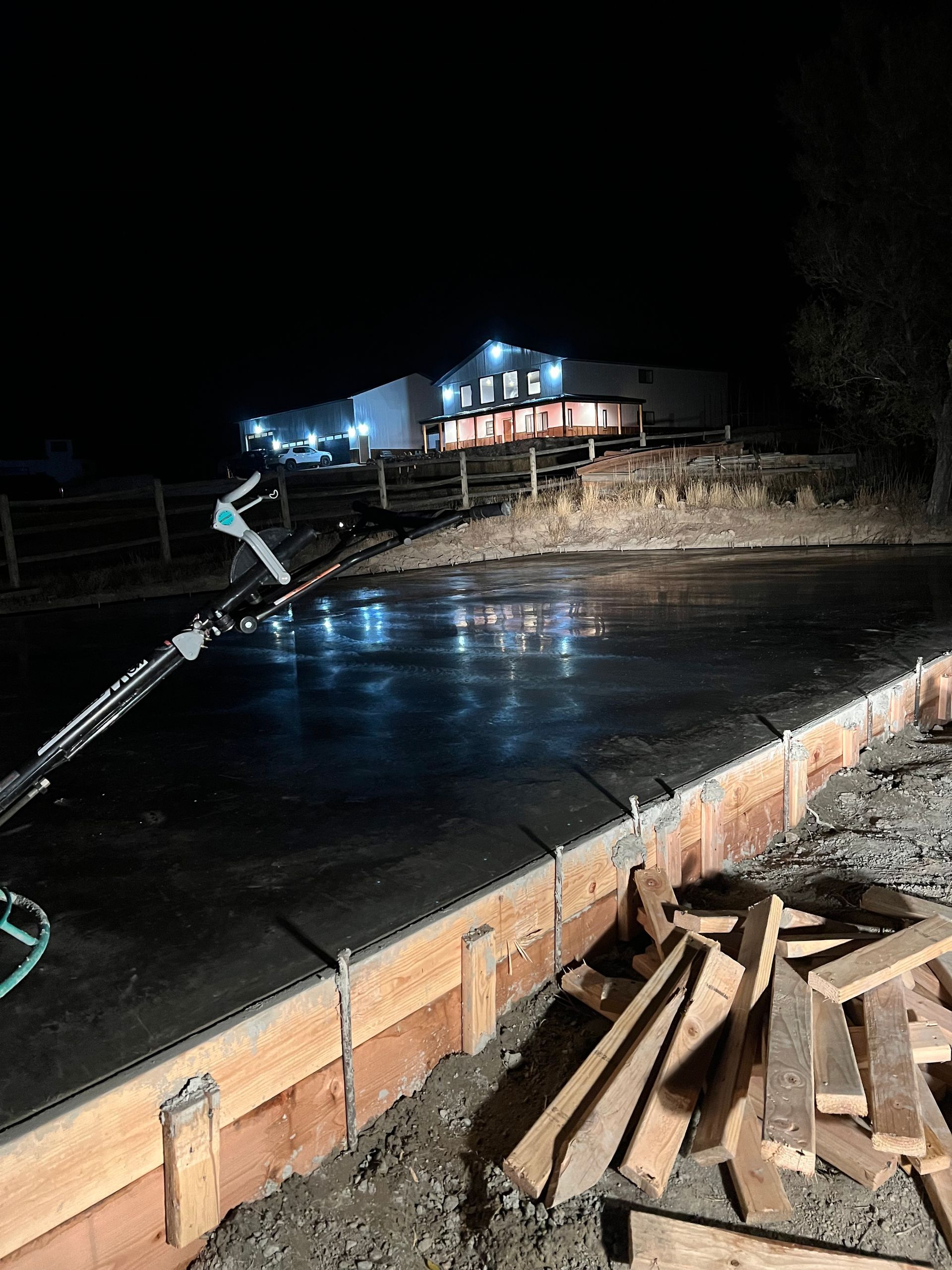 A construction site at night with a building in the background.