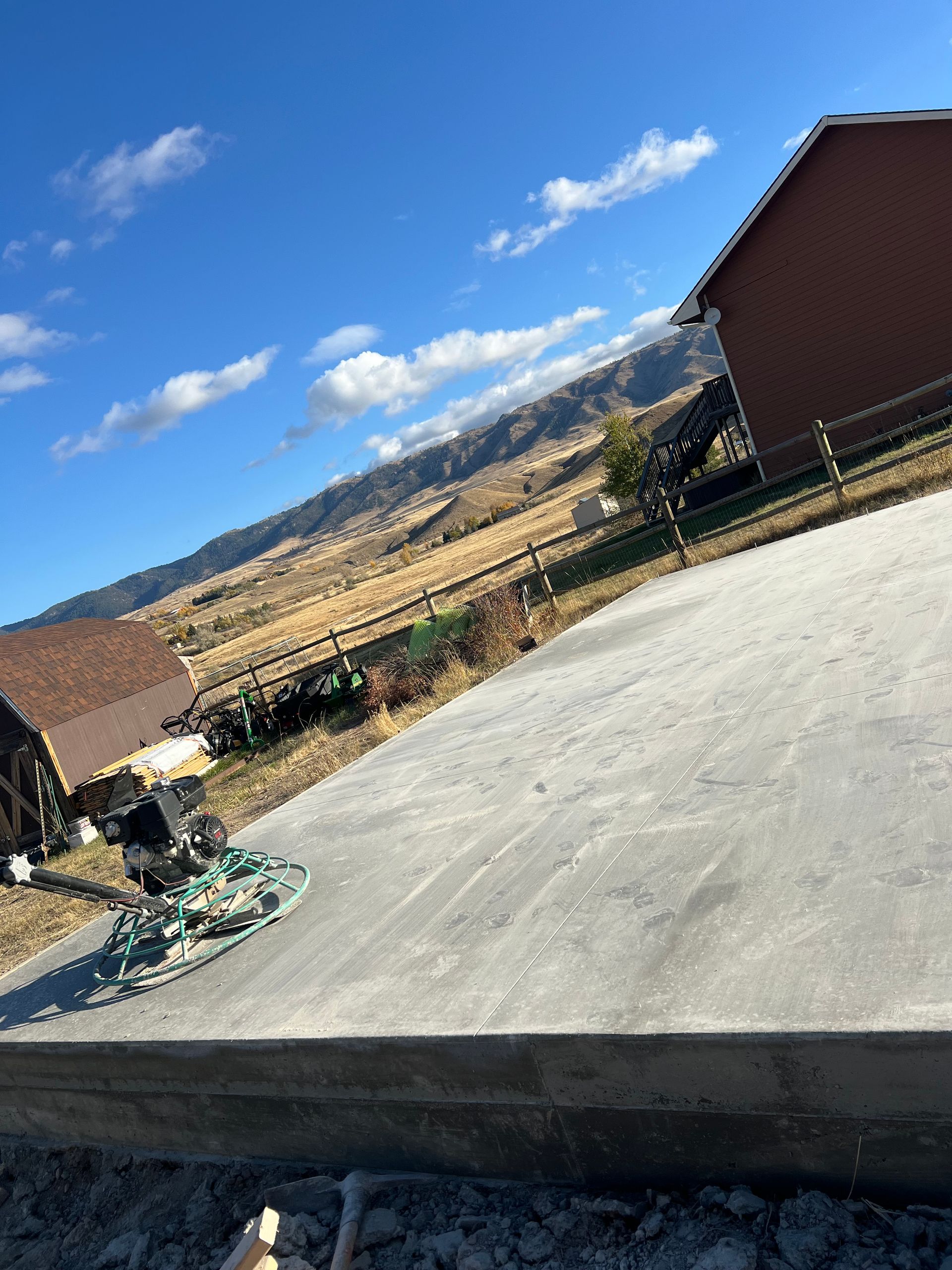 A concrete driveway with a house in the background