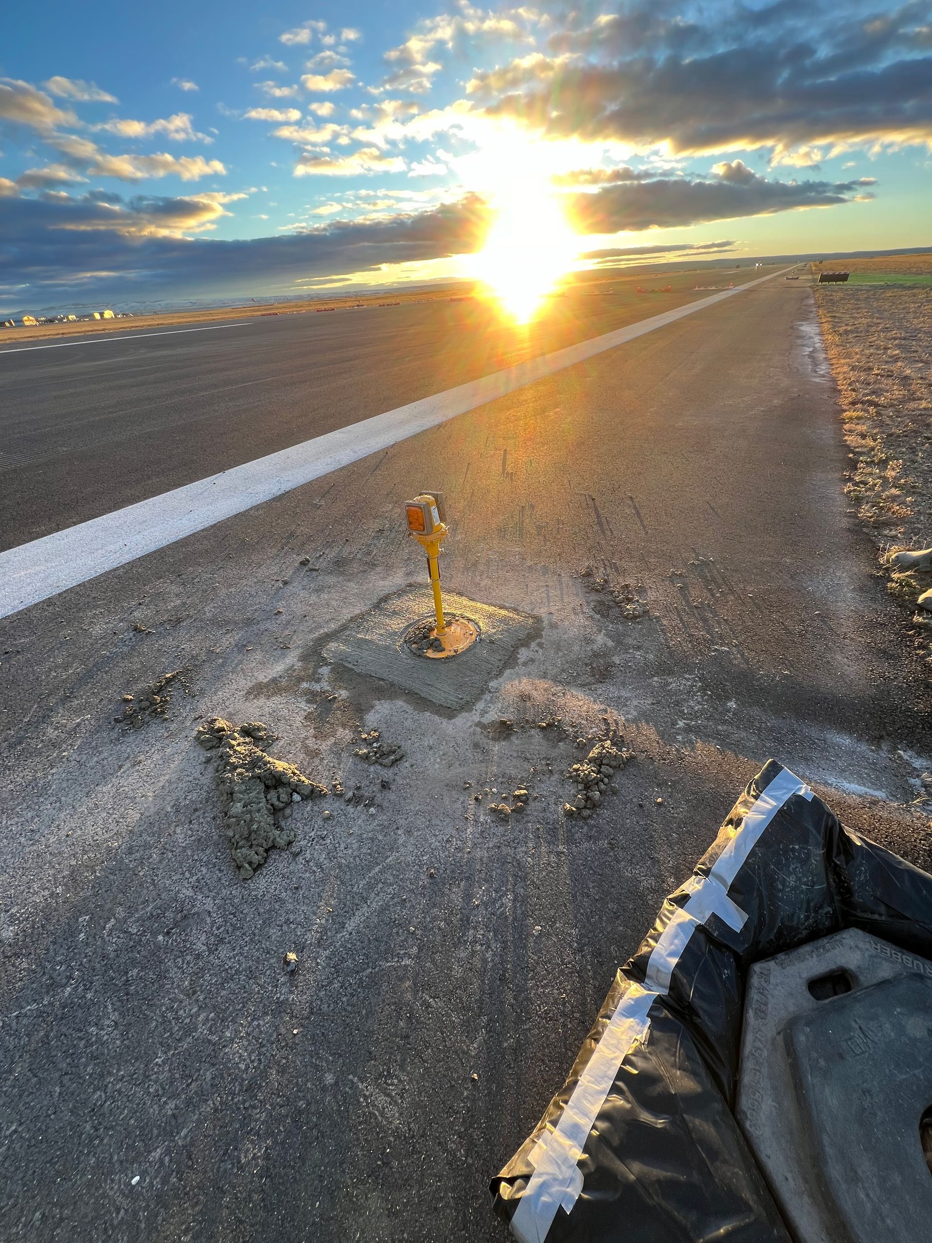 The sun is setting over a road with a hole in it