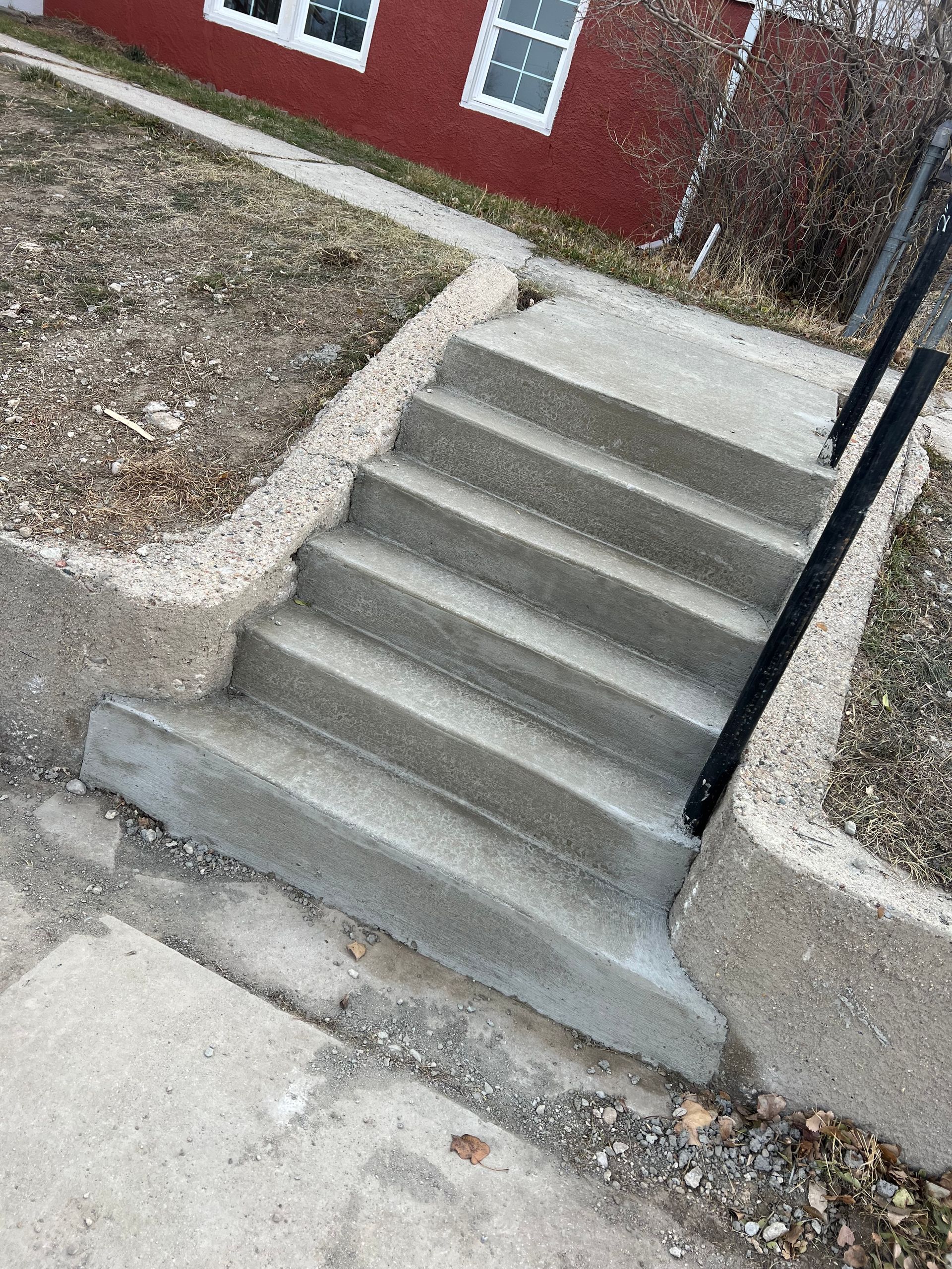 A set of concrete stairs leading up to a red house.
