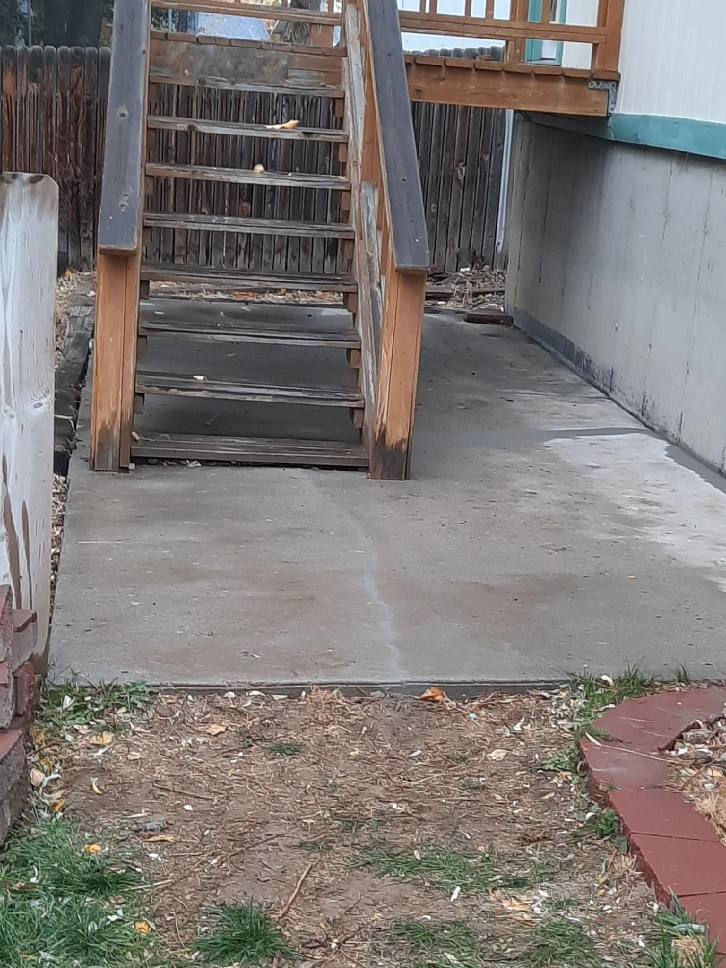 A wooden staircase is leading up to a concrete walkway.