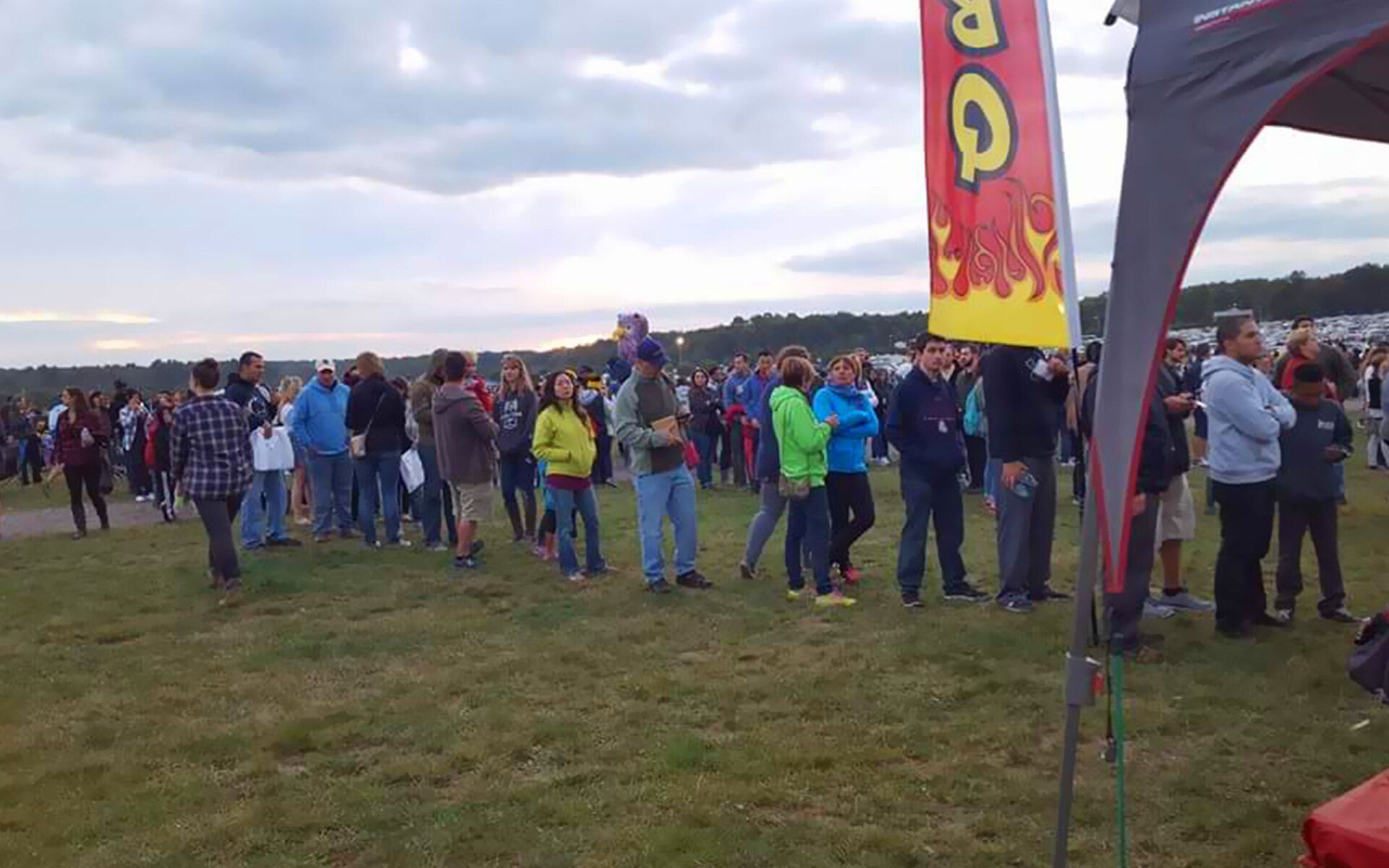 A group of people standing in a field for BBQ event
