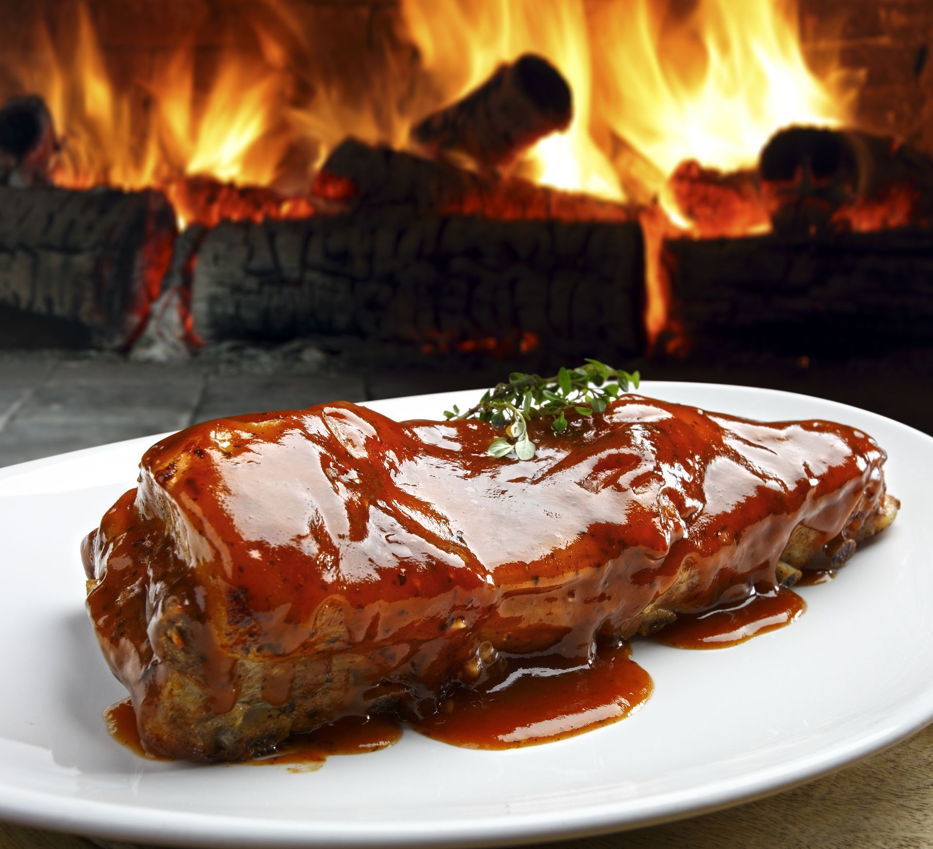 A white plate with a piece of meat on it in front of a fireplace