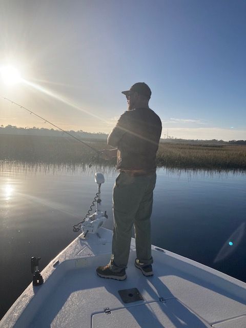 A man is fishing on a boat in the water.