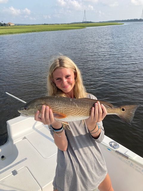 A woman is holding a large fish on a boat.