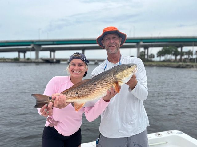 A man and a woman are holding a large fish on a boat.