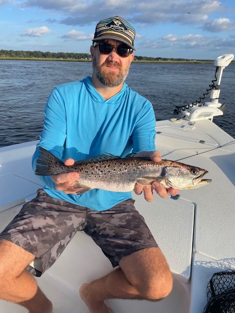 A man is sitting on a boat holding a fish