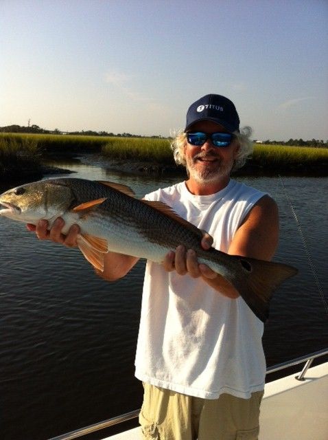 A man on a boat is holding a large fish
