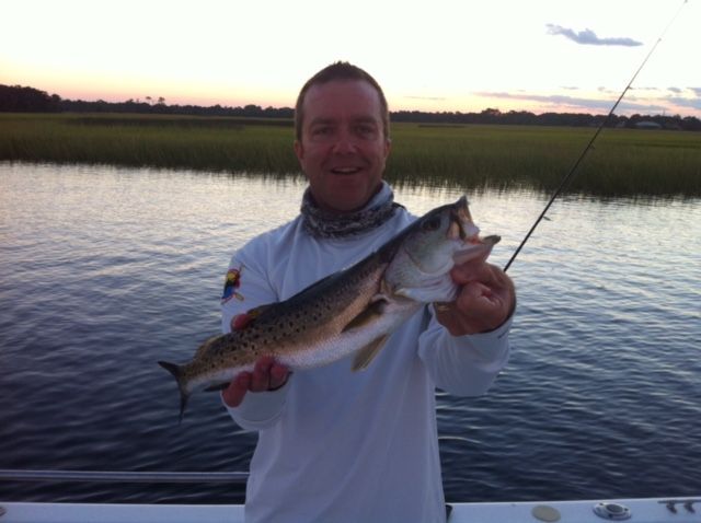 A man in a white shirt is holding a fish in his hands