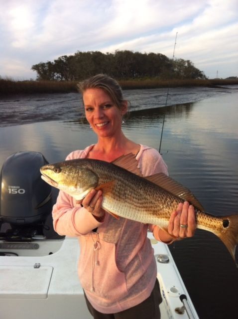 A woman is holding a large fish in front of a yamaha boat