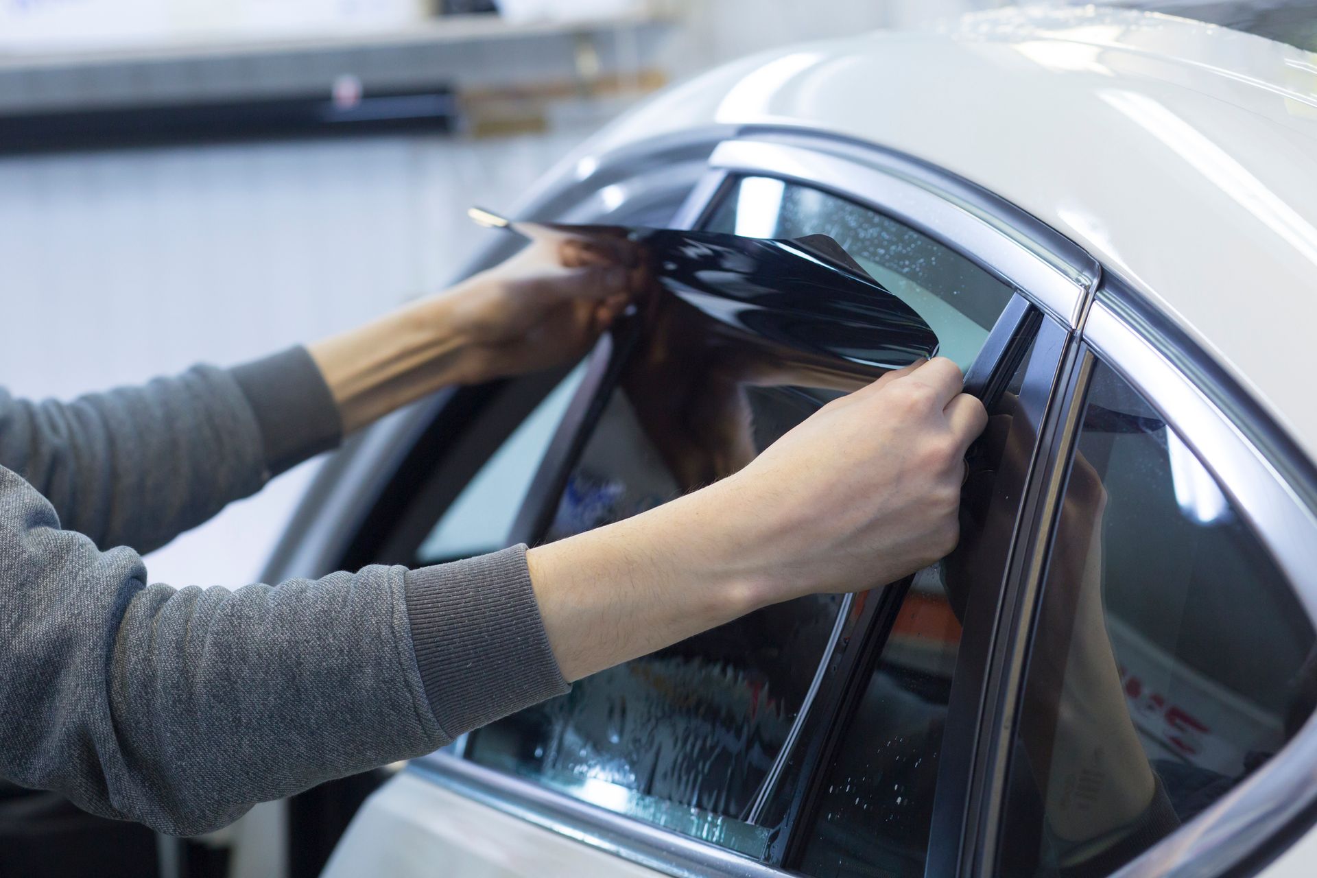 Una persona está aplicando una película tintada para ventanas a la ventana de un automóvil.