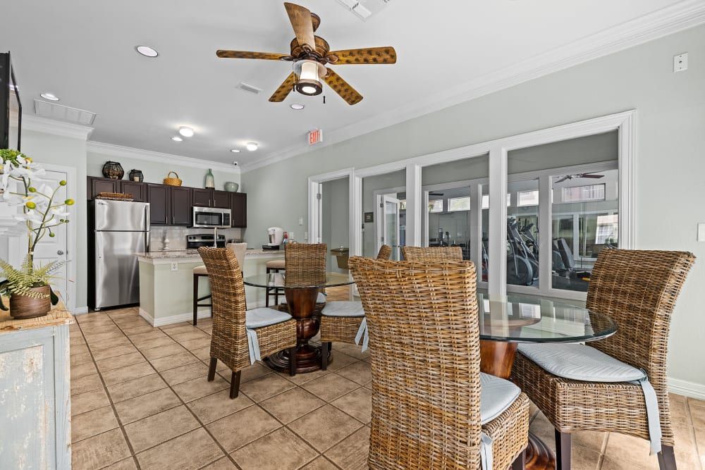 a room with wicker chairs, a table, and a ceiling fan at Marquis at Ladera Vista in Austin, TX.