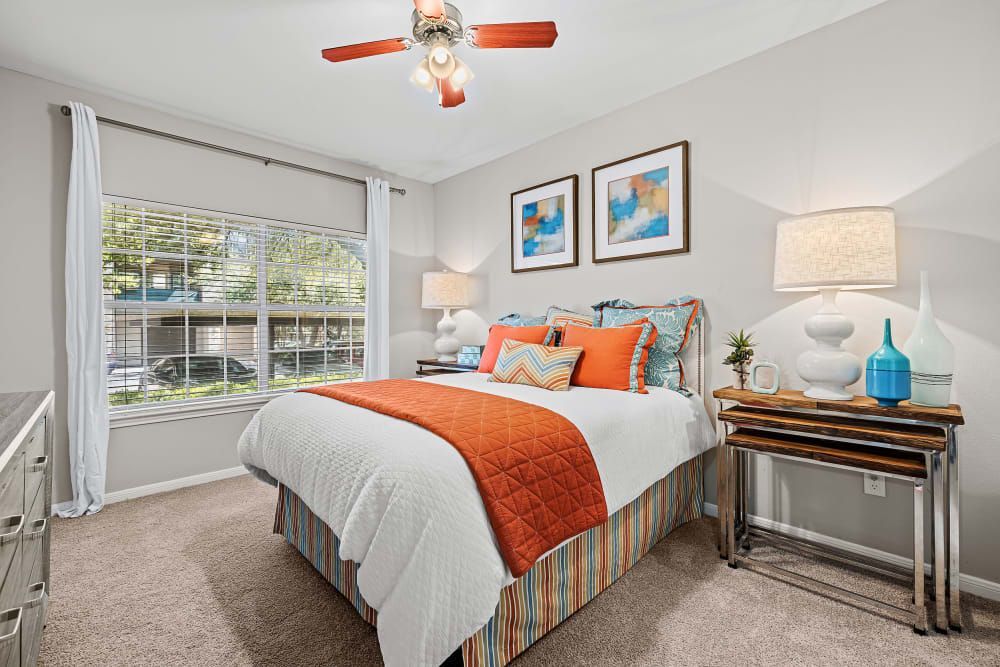 a bedroom with a bed, ceiling fan, lamps, and a large window at Marquis at Ladera Vista in Austin, TX.
