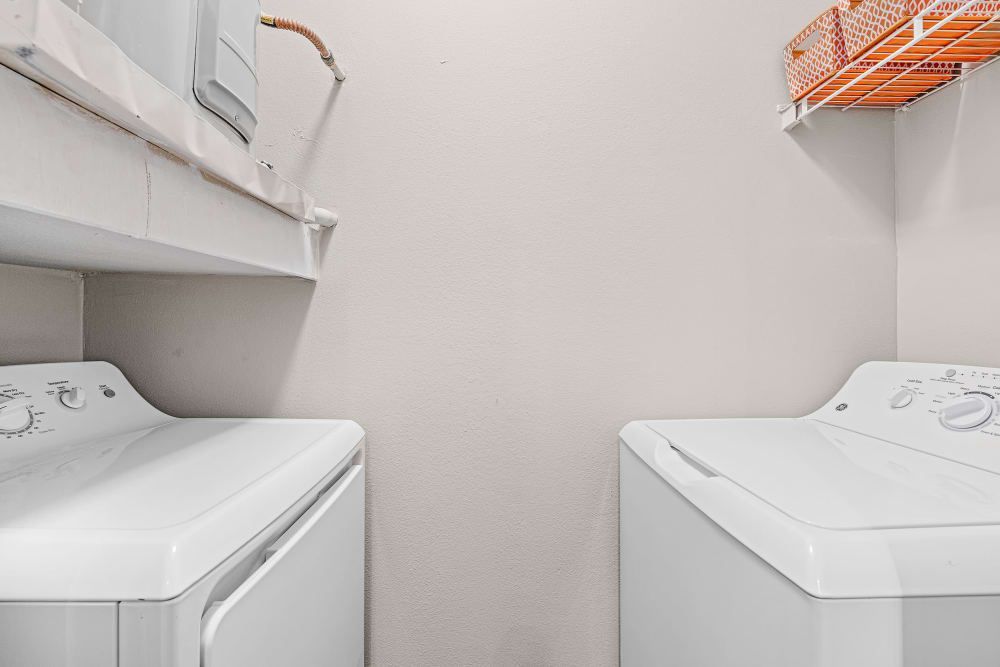 a laundry room with two white washers and dryers at Marquis at Ladera Vista in Austin, TX.