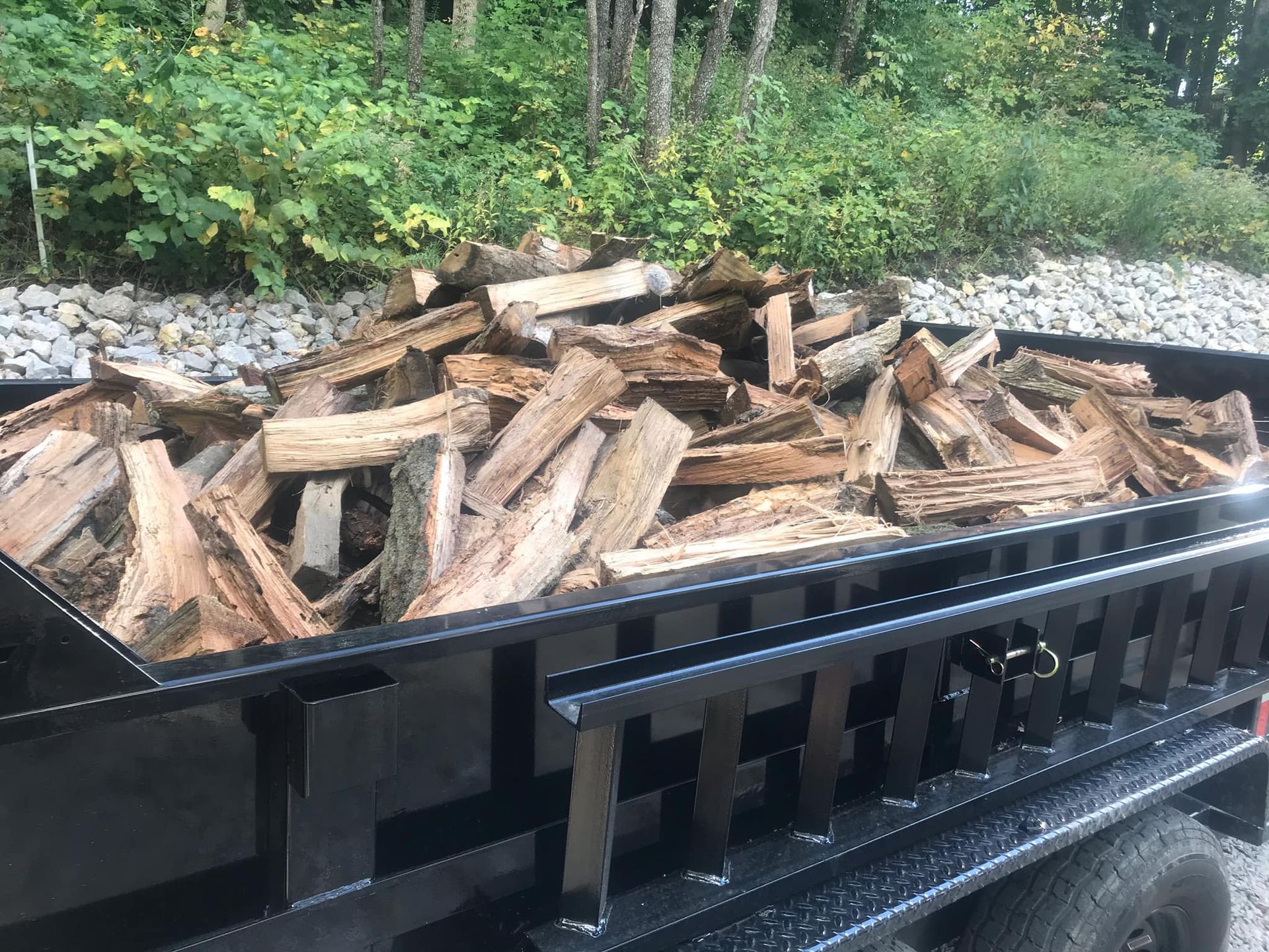A trailer filled with wood is parked on the side of the road.