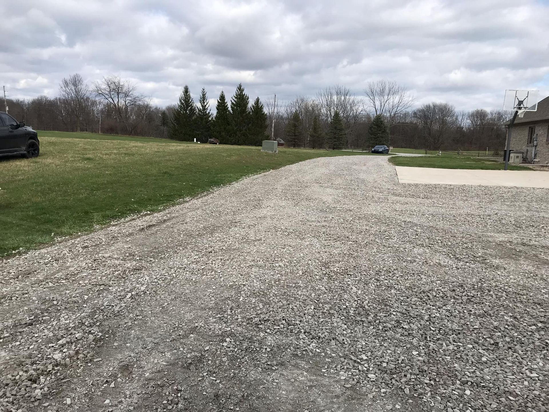 A gravel driveway leading to a house with a car parked on the side of it.