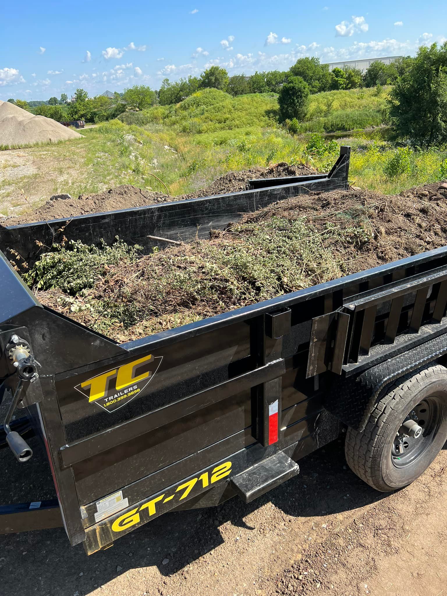 A dump truck with a trailer full of dirt is parked on the side of the road.