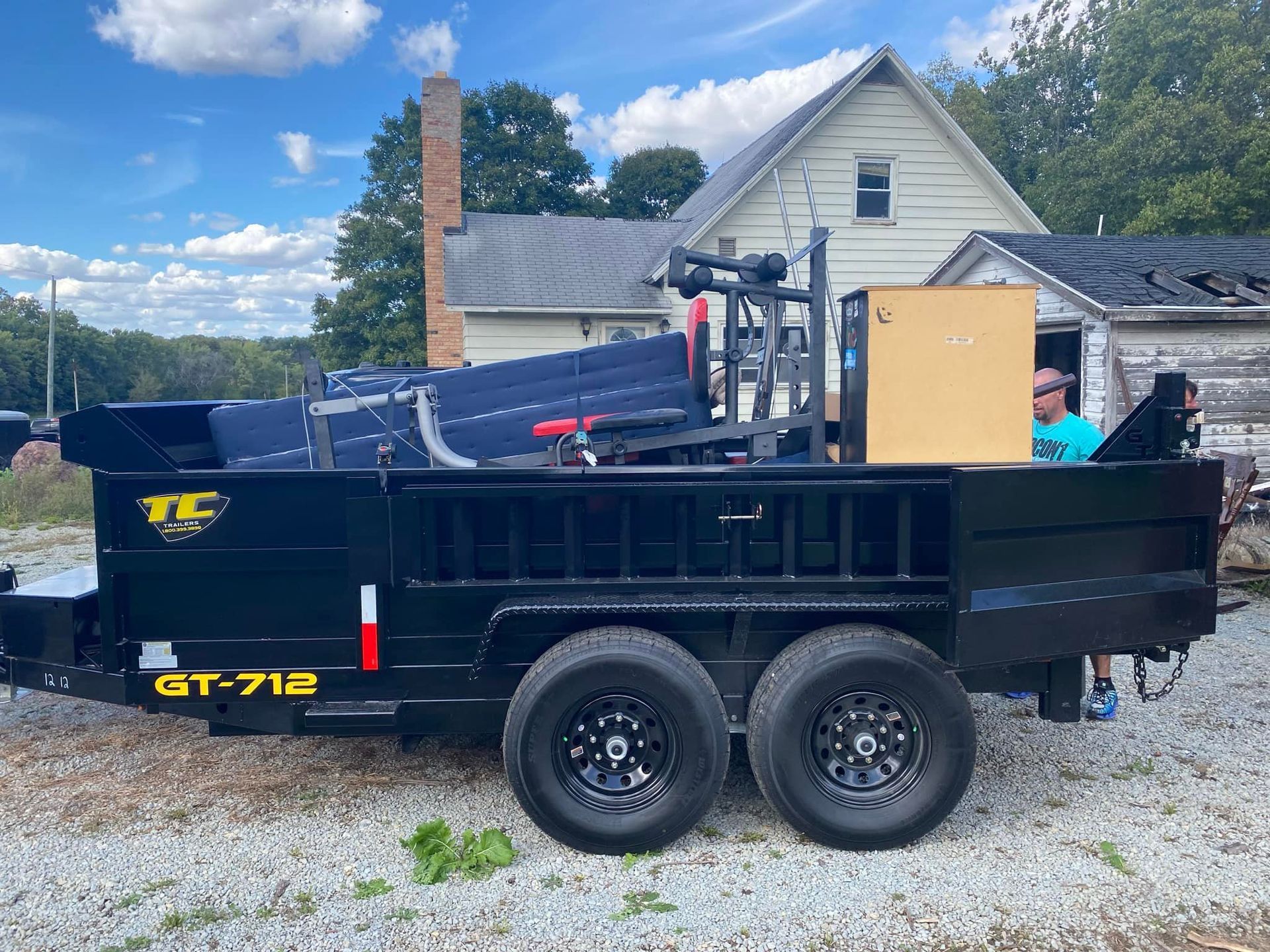 A dump trailer is parked in front of a house.