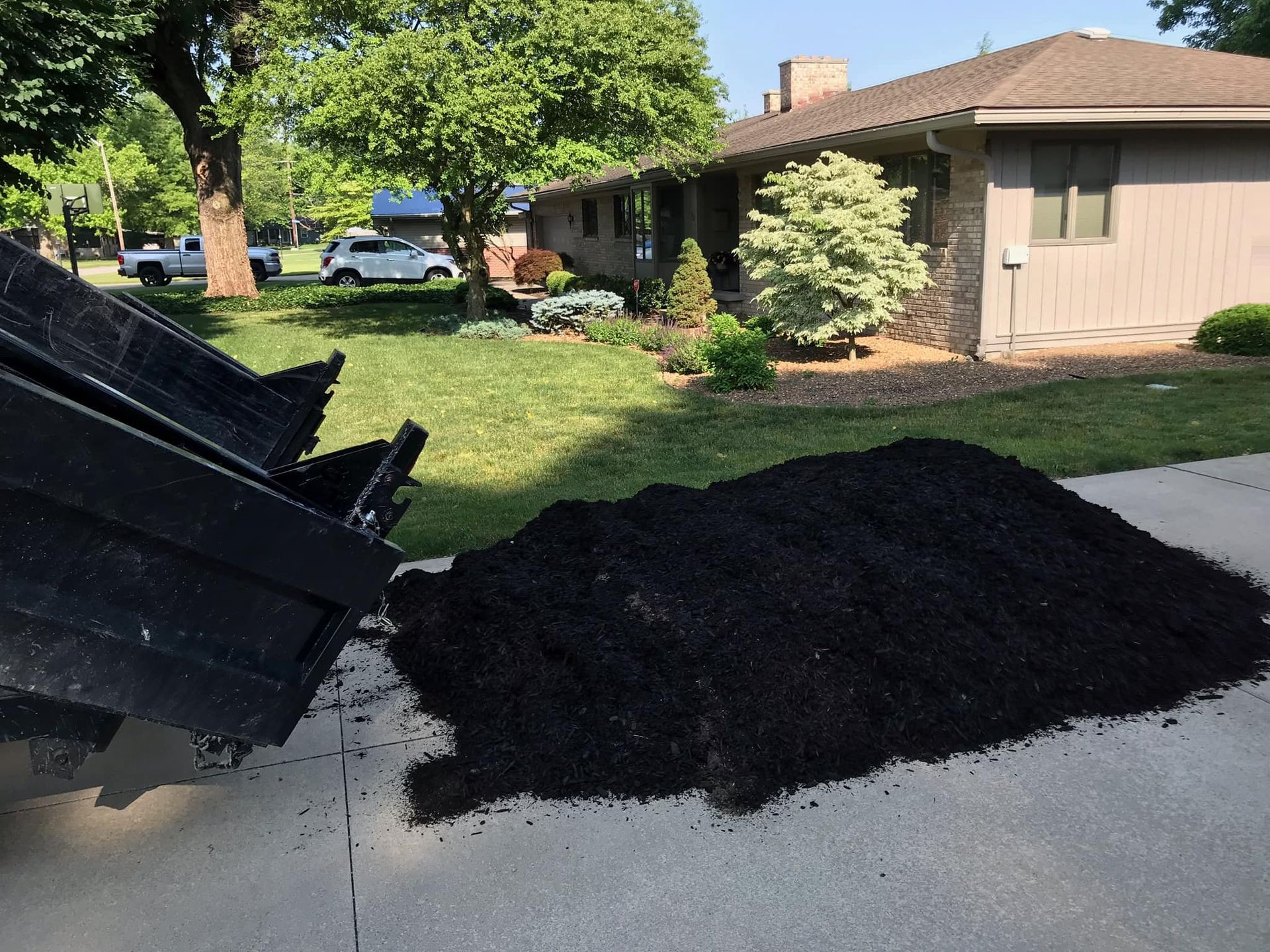 A pile of mulch is sitting on the sidewalk in front of a house.