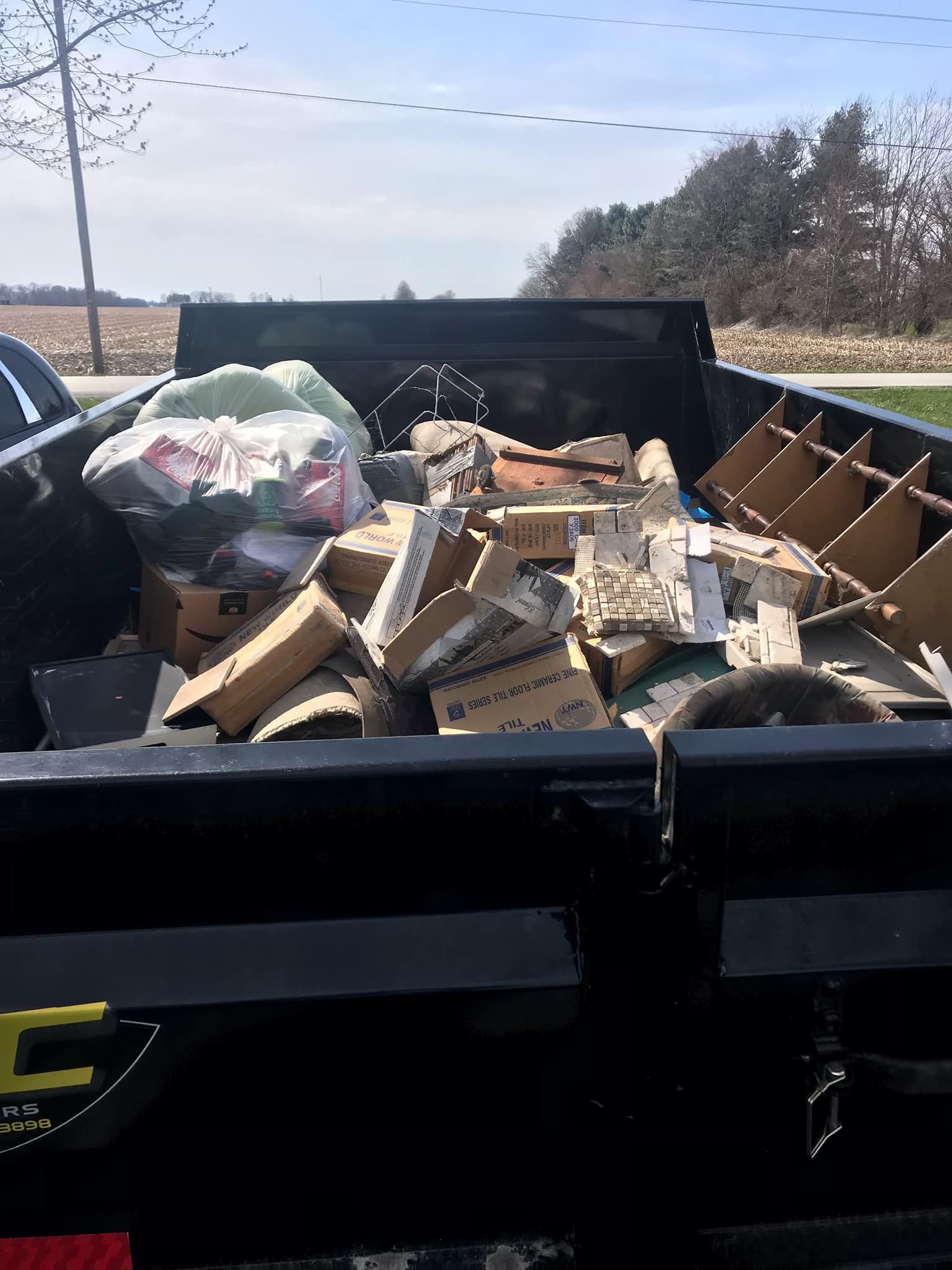 A dumpster filled with lots of cardboard boxes and trash.