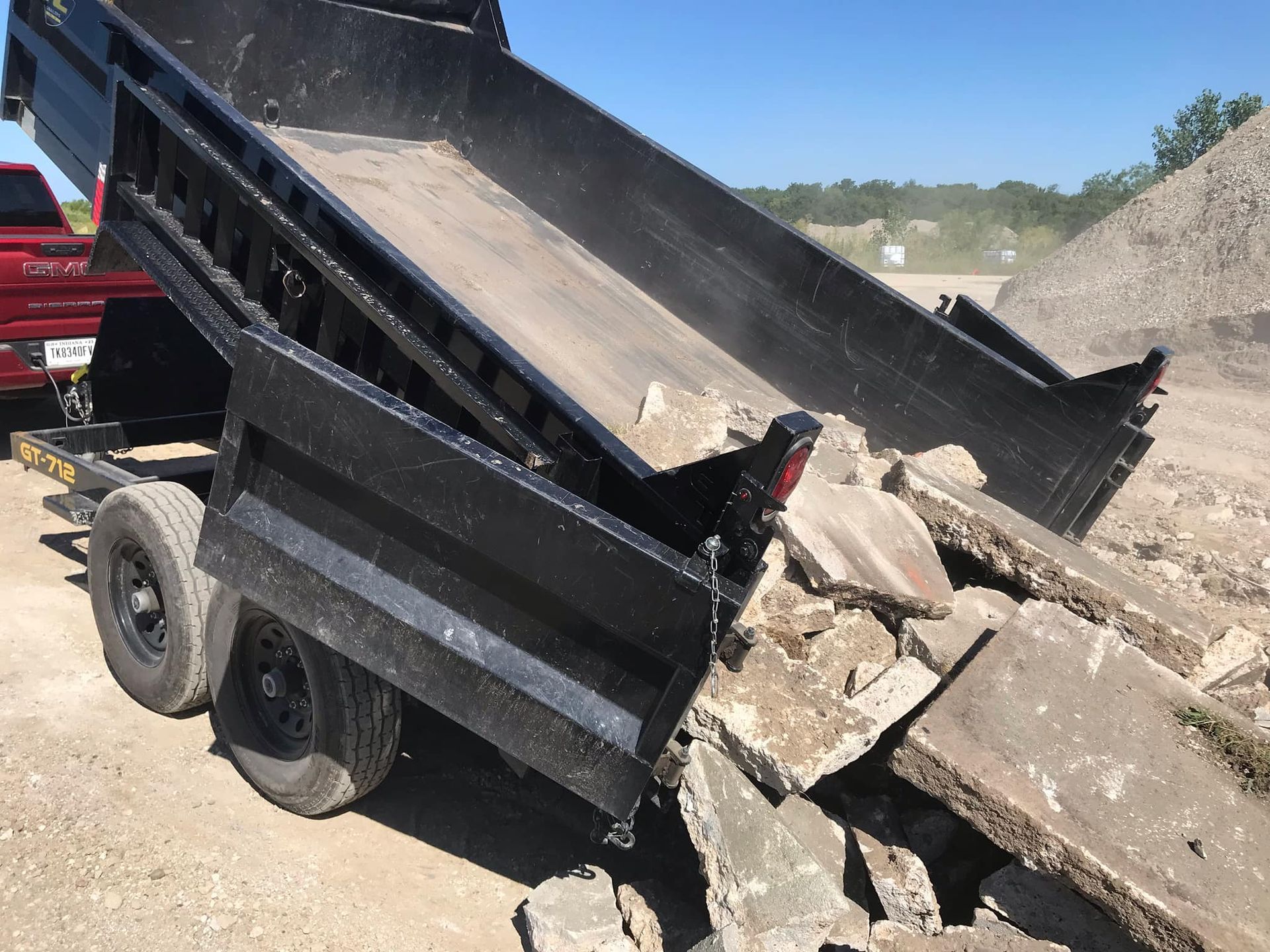A dump truck is dumping rocks on a trailer.
