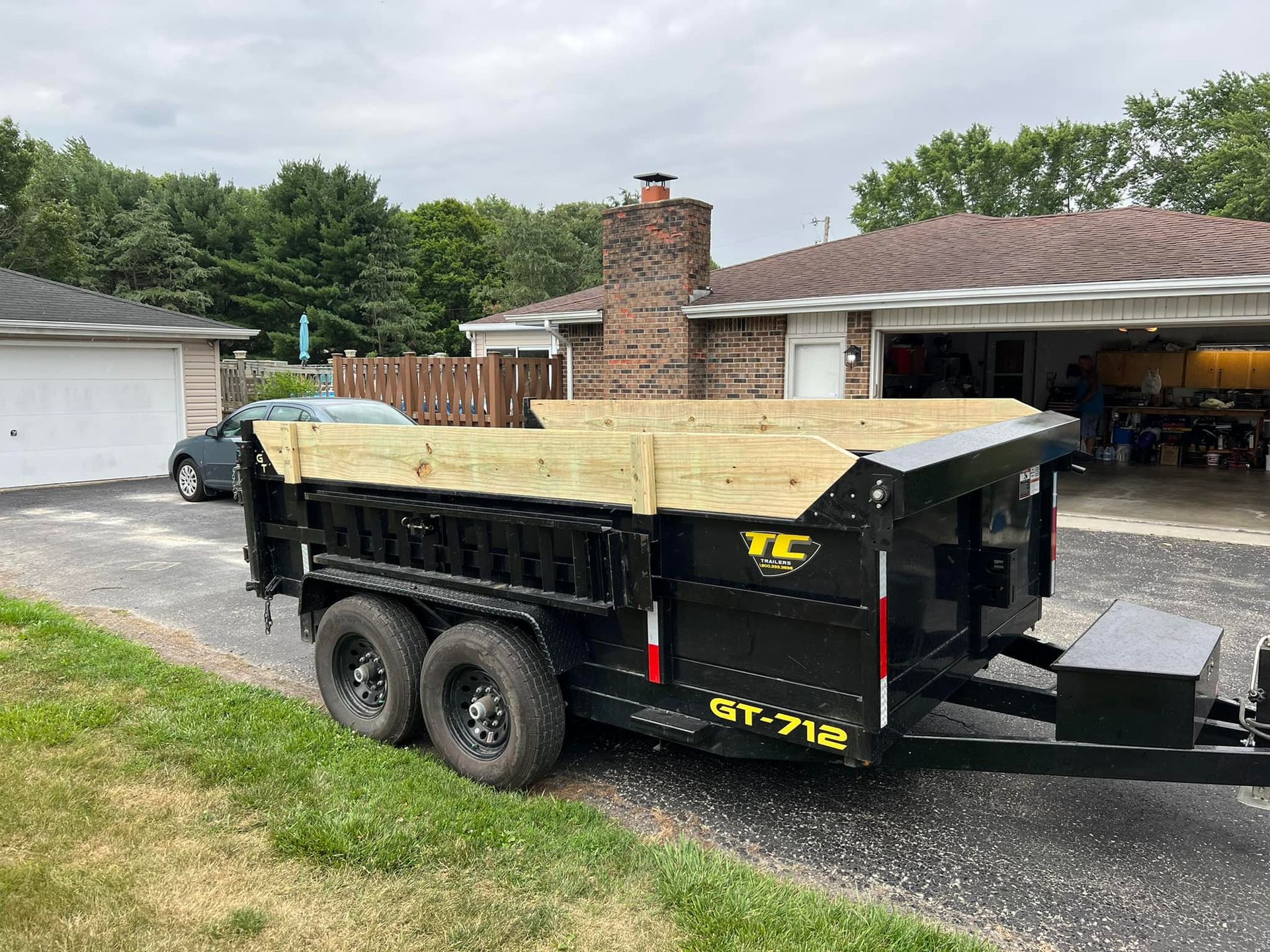 A dump trailer is parked in front of a house.
