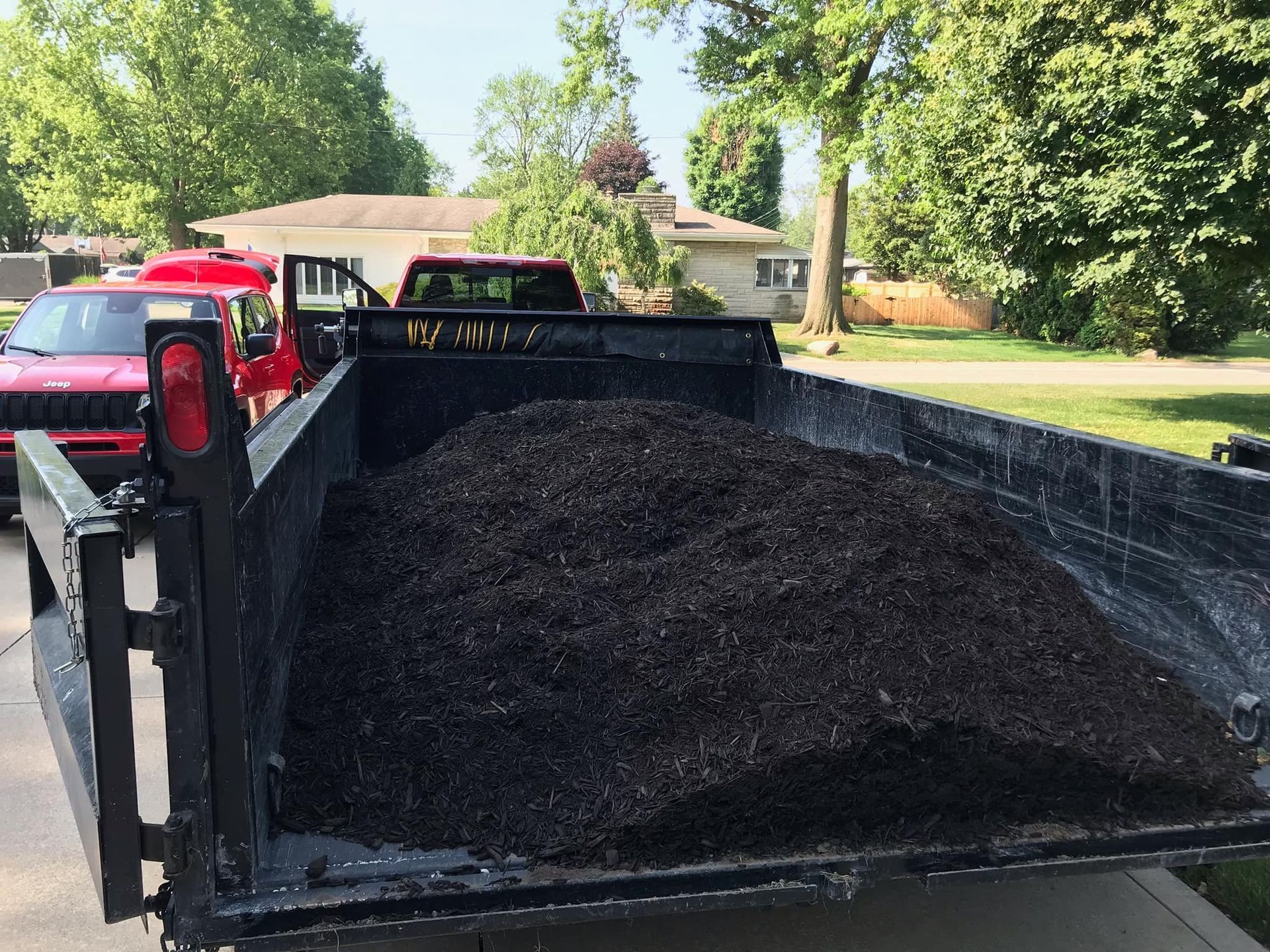 A dump truck filled with dirt is parked in a driveway.
