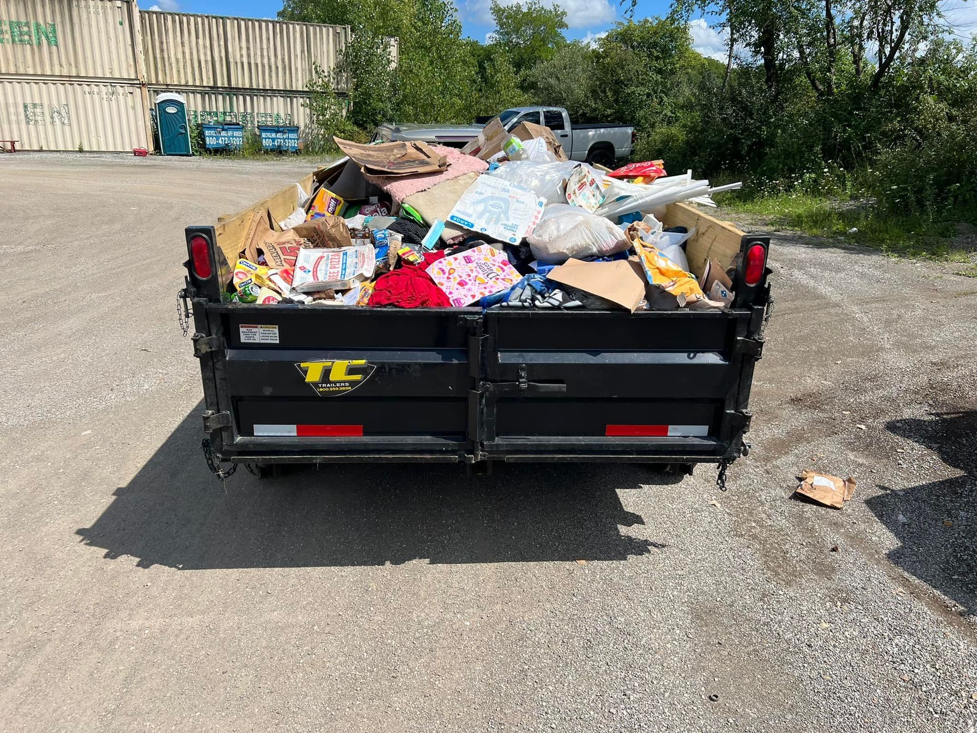 A dumpster filled with trash is parked in a parking lot.