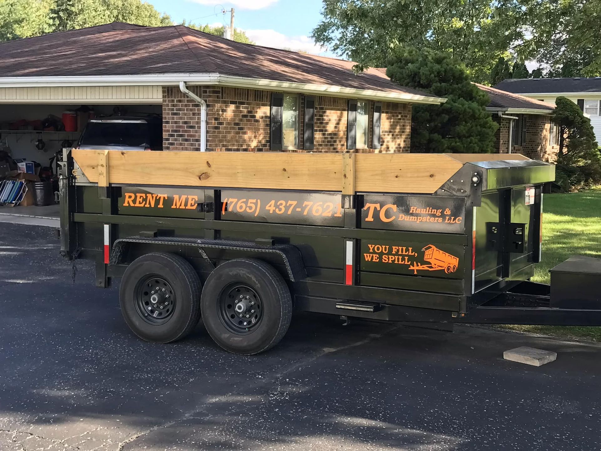A dumpster trailer is parked in front of a house.