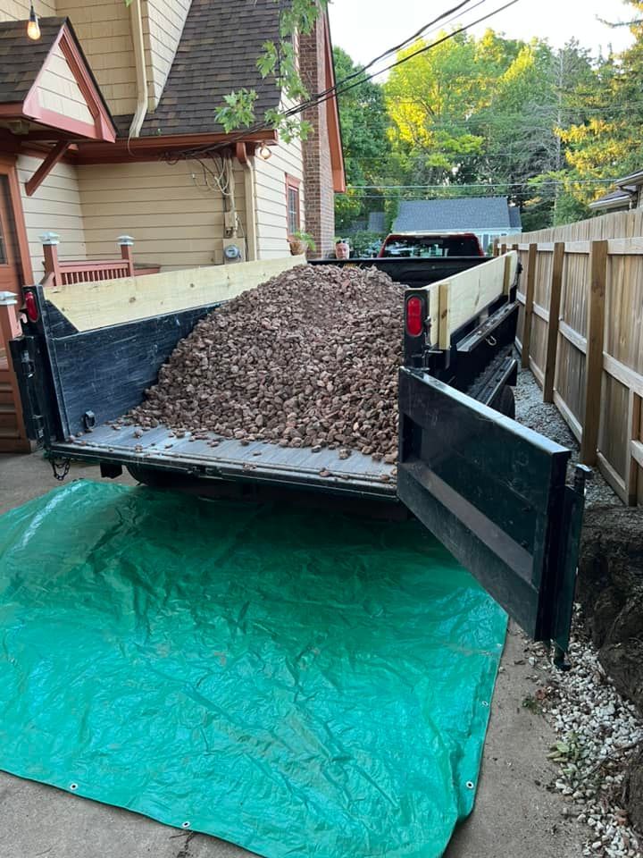 A dump truck filled with mulch is parked in front of a house.