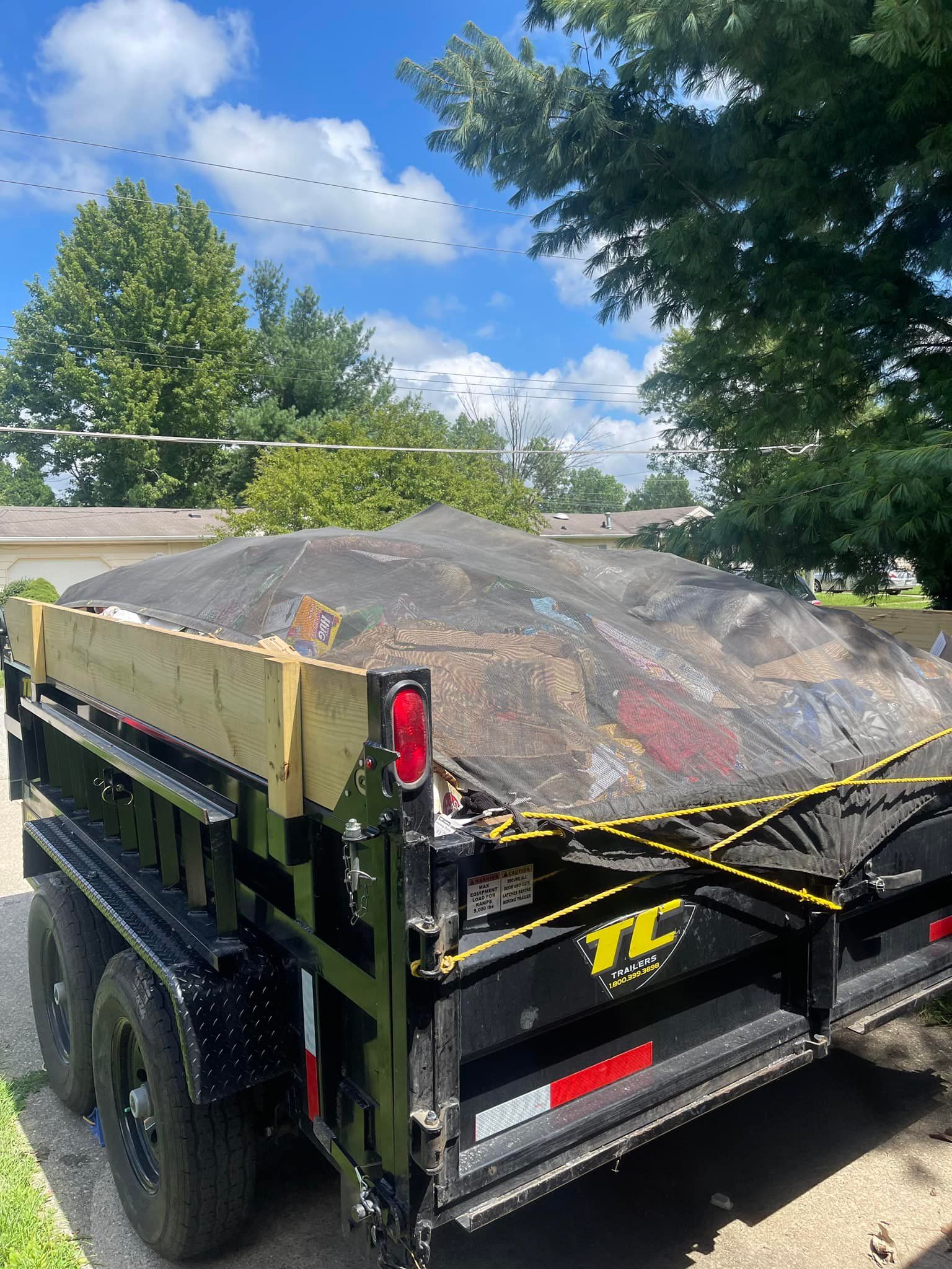 A dump truck with a tarp on top of it is parked on the side of the road.