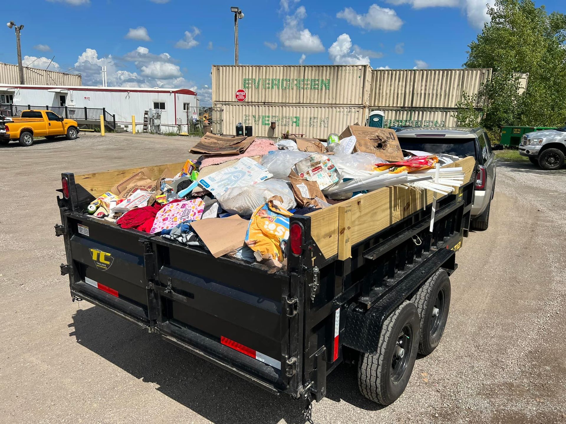 A dumpster filled with trash is parked in a parking lot.
