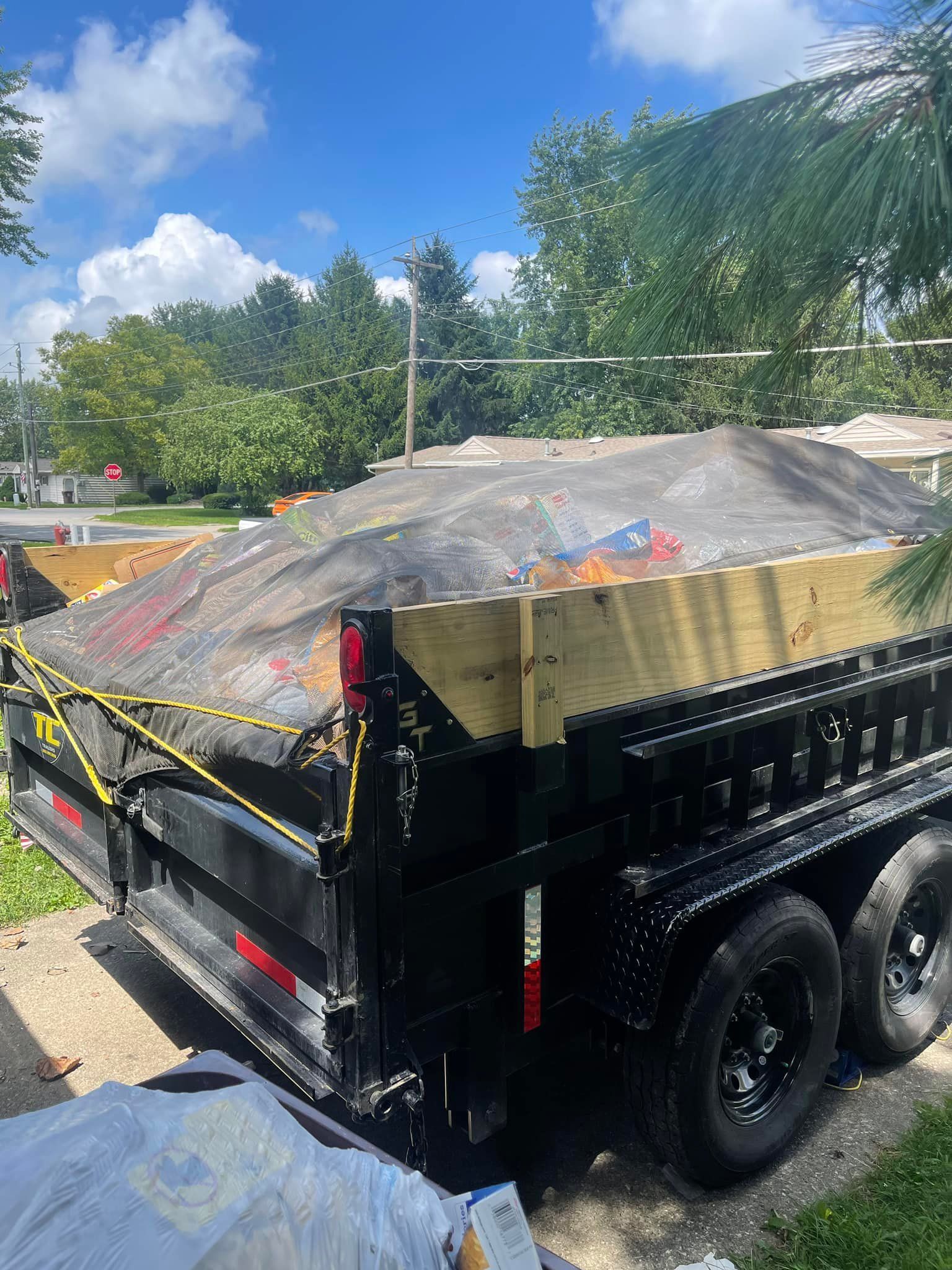 A dumpster with a tarp on top of it is parked on the side of the road.