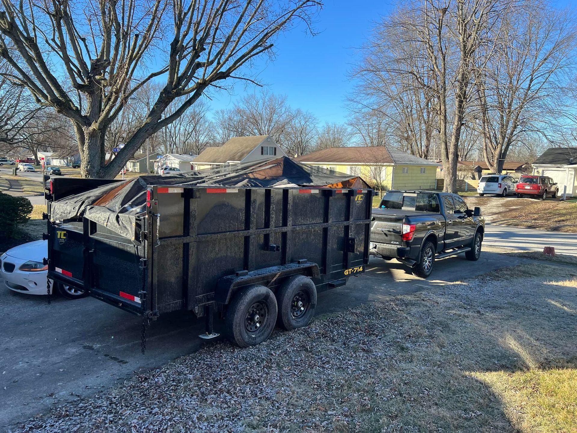 A dumpster trailer is parked in a driveway next to a truck.