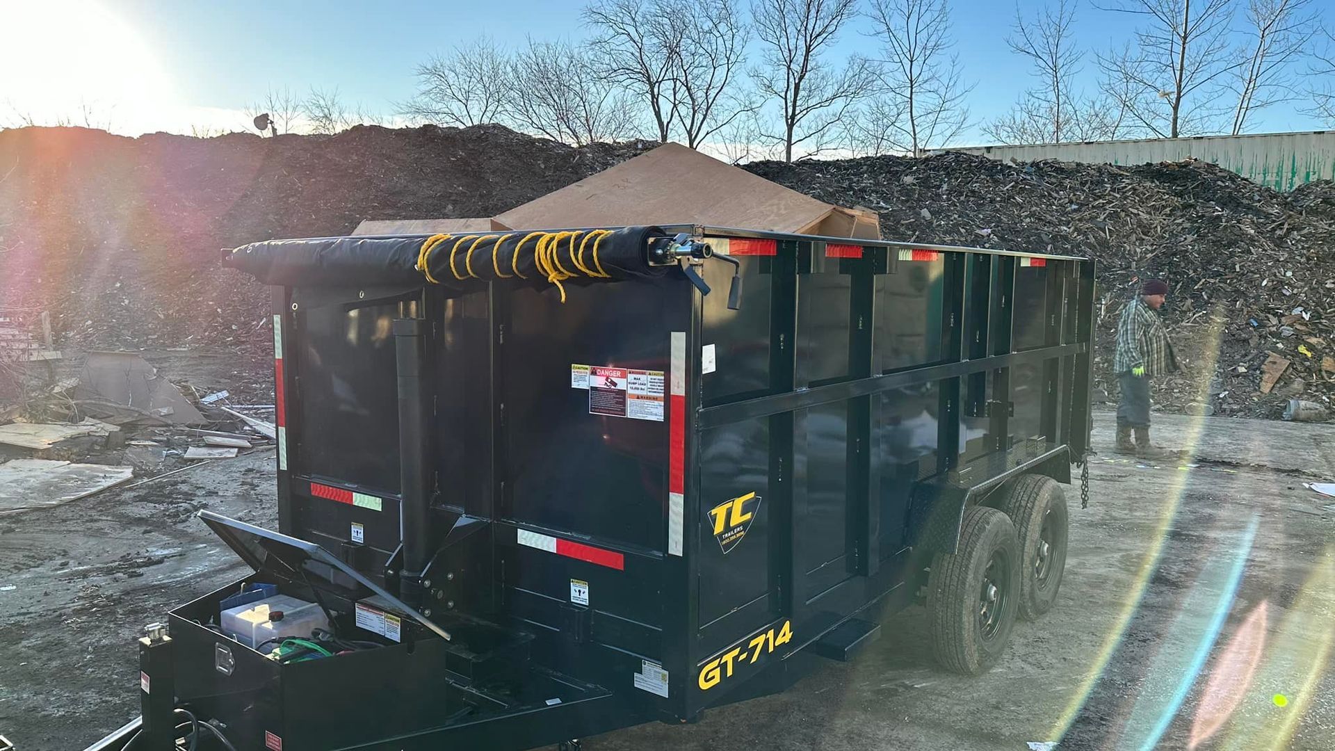 A dump truck is parked in front of a pile of trash.