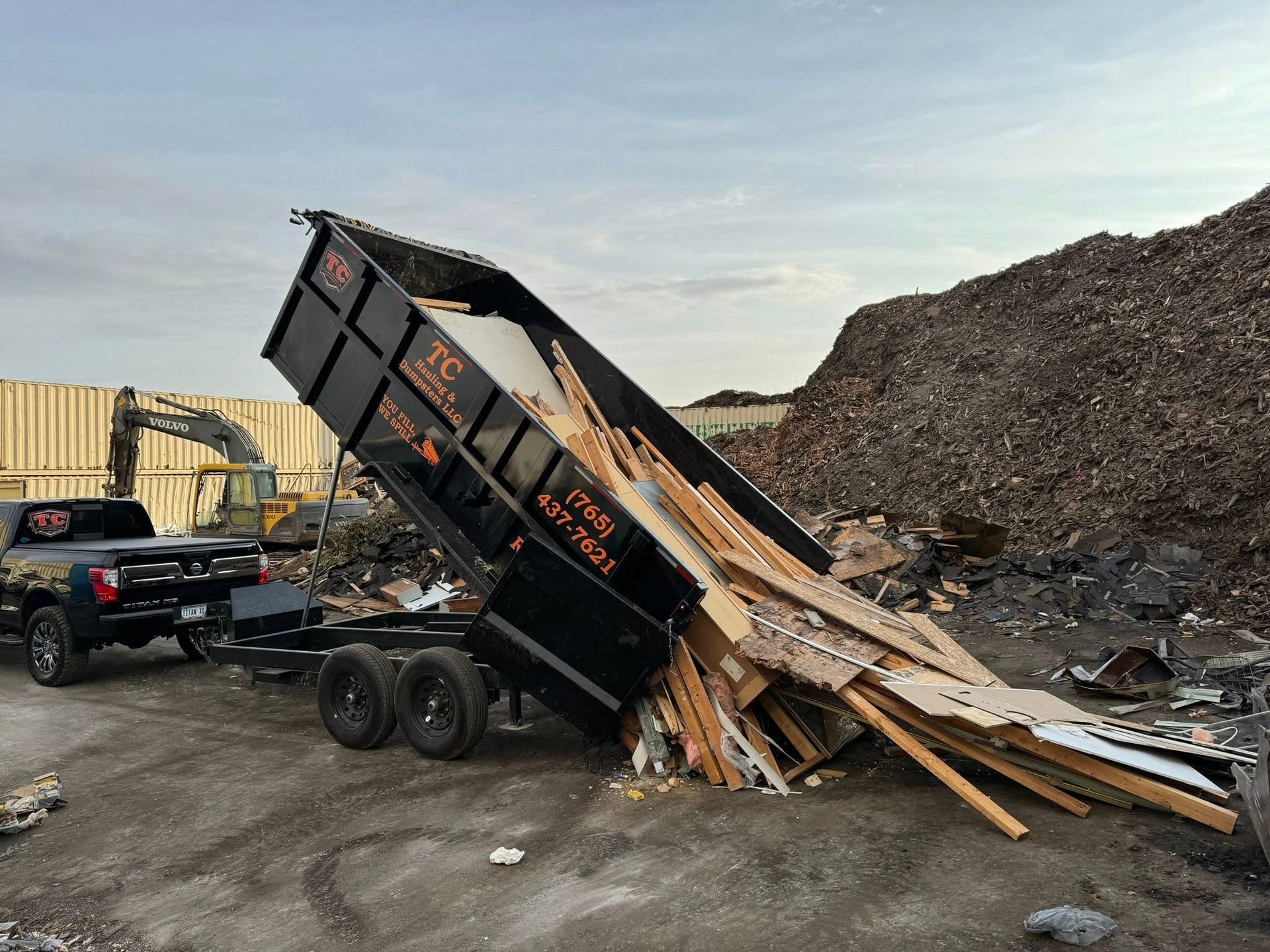 A dumpster is sitting on top of a pile of wood.