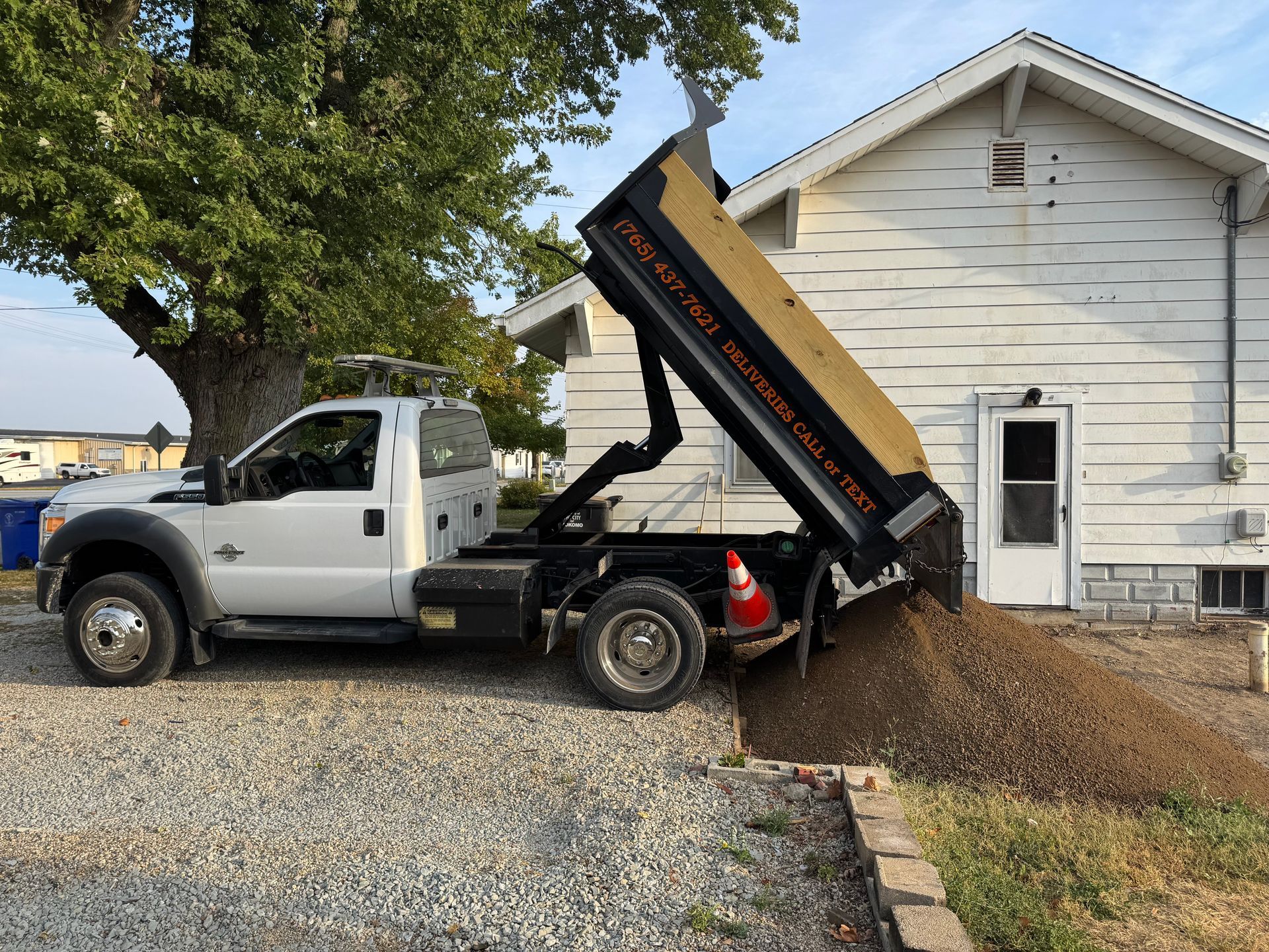 A dumpster trailer is parked in a parking lot in front of a brick building.