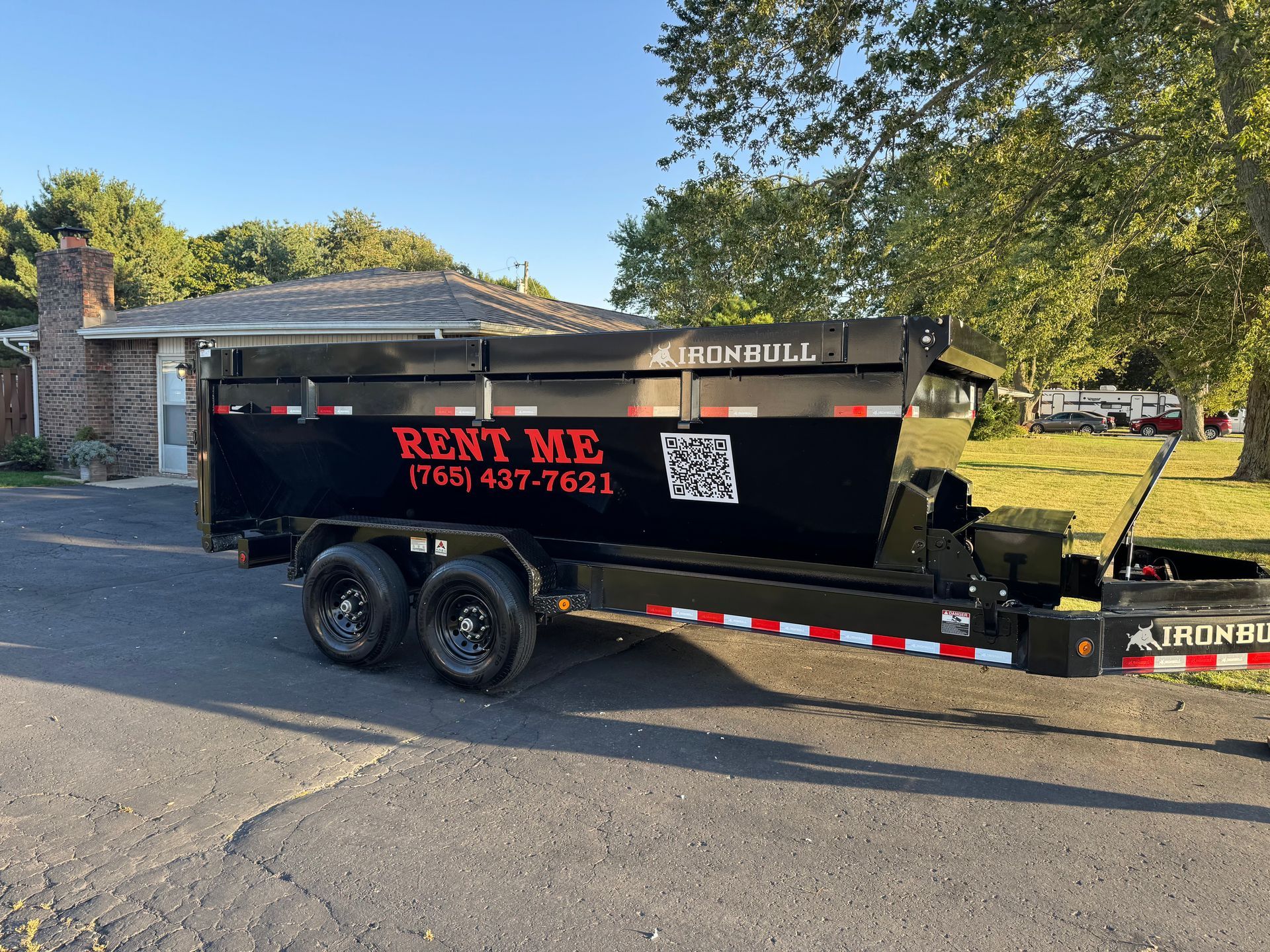 A black dump trailer parked on a residential driveway with 