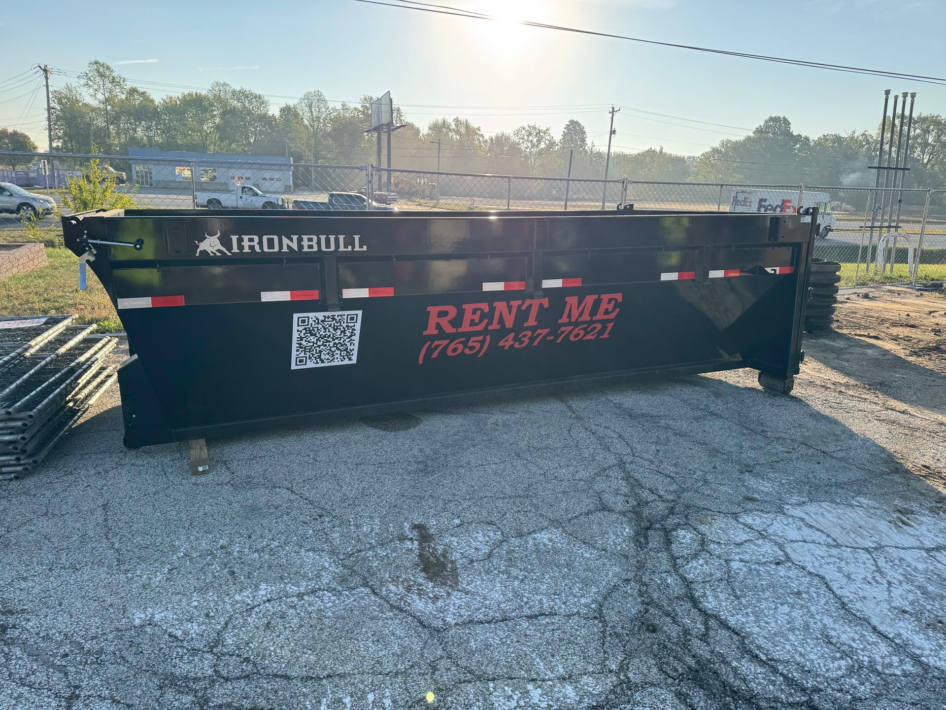 A black Iron Bull roll-off dumpster sitting on a gravel lot with 