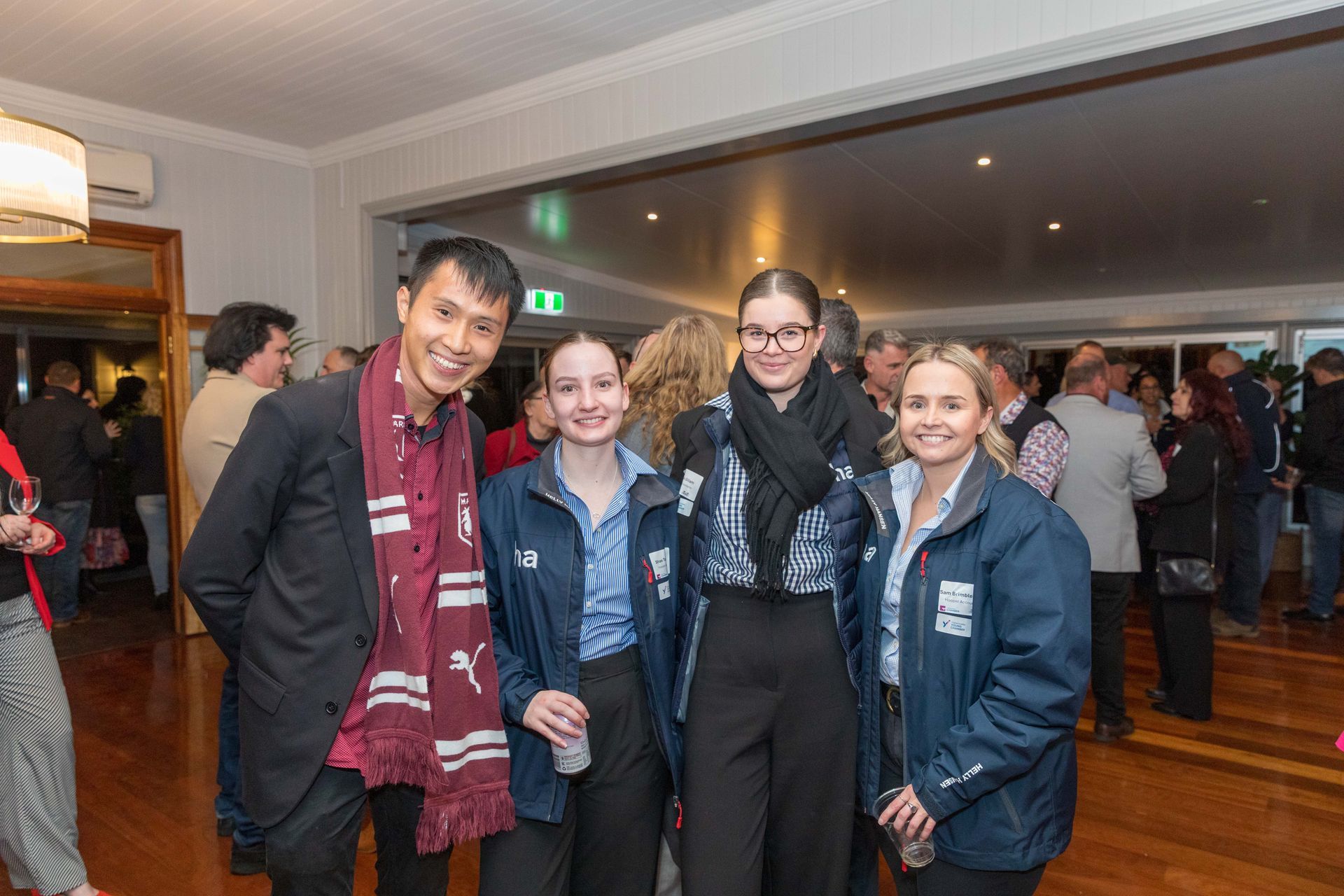 A group of people pose for a photo at an event. Four young people and a man smile at the camera.