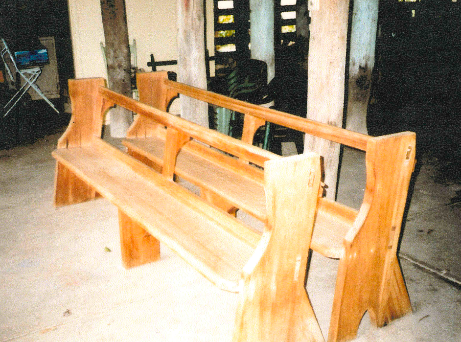 Wooden benches with high backs, set outside. The light wood has a warm tone.