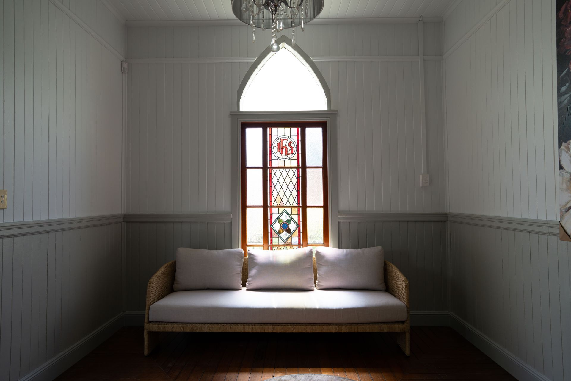 Two white churches with grey roofs on a green lawn, framed by trees; sunny day.