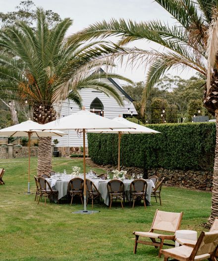 Wedding ceremony setup in a lavender field with a flower-covered altar and wooden benches facing a scenic valley at sunset.