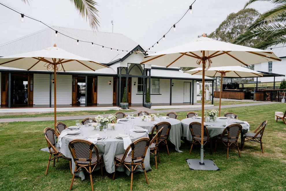 A white building with a green lawn and palm trees under a sunset sky. Entranceway with a covered patio.