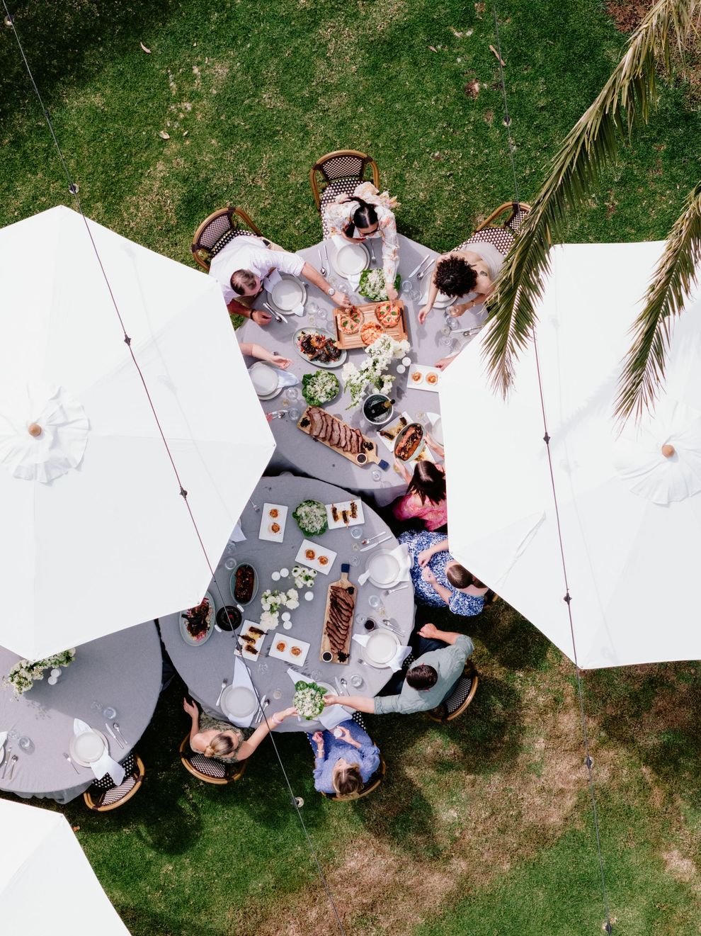 A dusk view of a large event venue with a long veranda, string lights, and a manicured lawn under a cloudy sky.