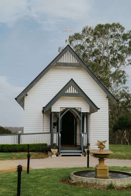 Inside of a wooden church, rows of pews face an altar with a large window. Sunlight streams in, illuminating the interior.